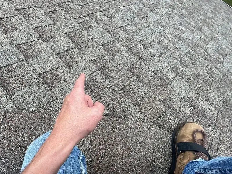 image of a shingle roof with the hand and foot of the roof inspector showing in the image
